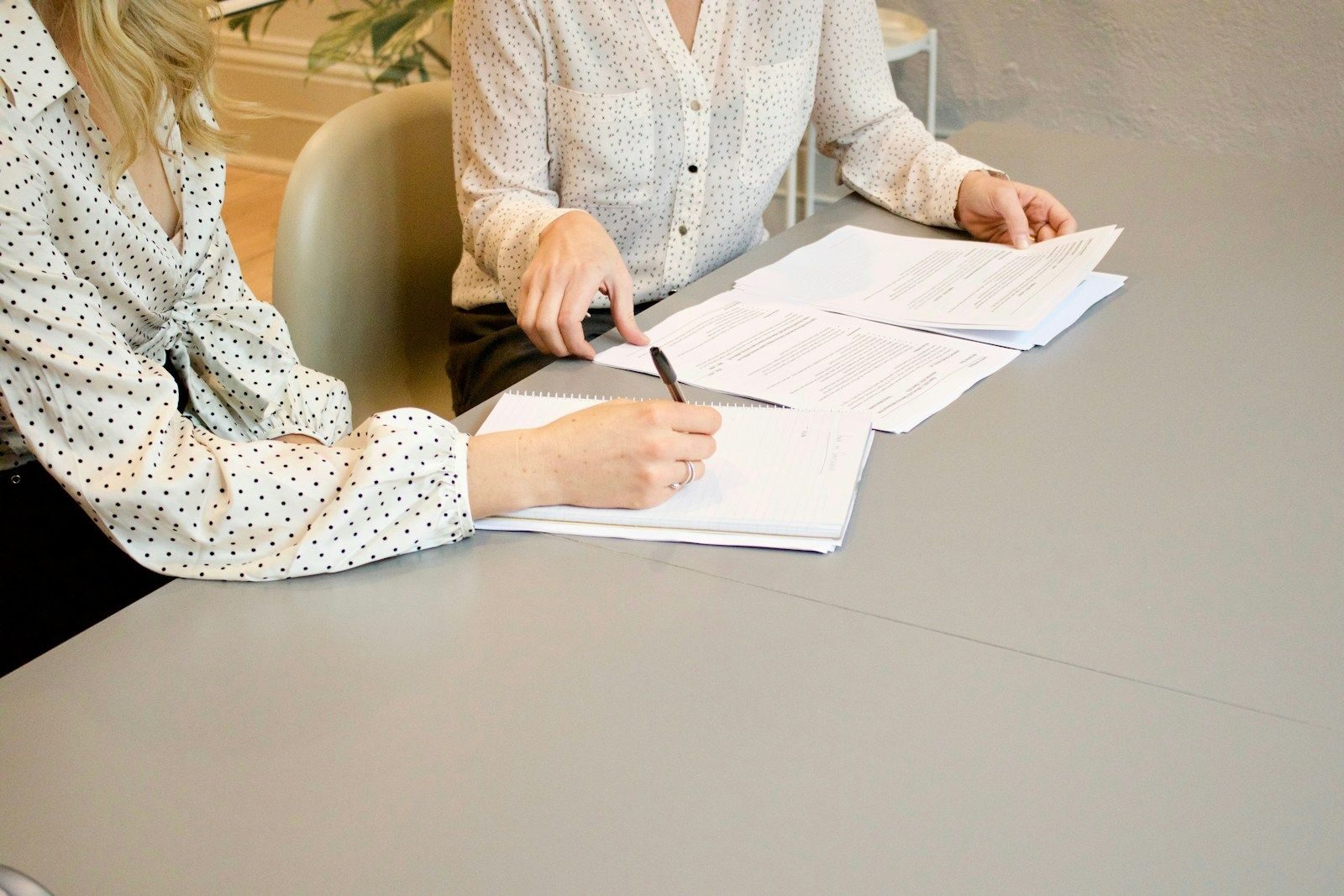 conciliateur de justice woman signing on white printer paper beside woman about to touch the documents