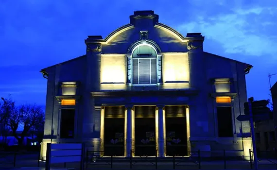 Photo du théâtre de Marseillan magnifiquement illuminé, mettant en valeur son architecture dans l'obscurité de la nuit.