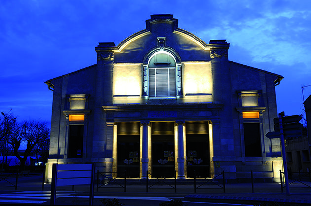 Photo du théâtre de Marseillan magnifiquement illuminé, mettant en valeur son architecture dans l'obscurité de la nuit.
