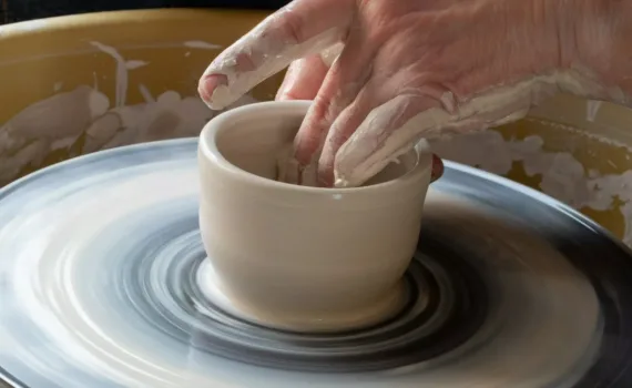 person making clay pot on white round plate