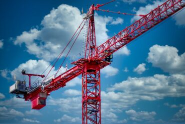 a large red crane sitting on top of a sandy beach