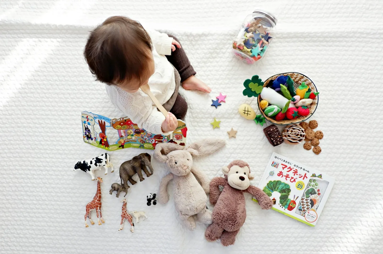 matinée des bébés boy sitting on white cloth surrounded by toys