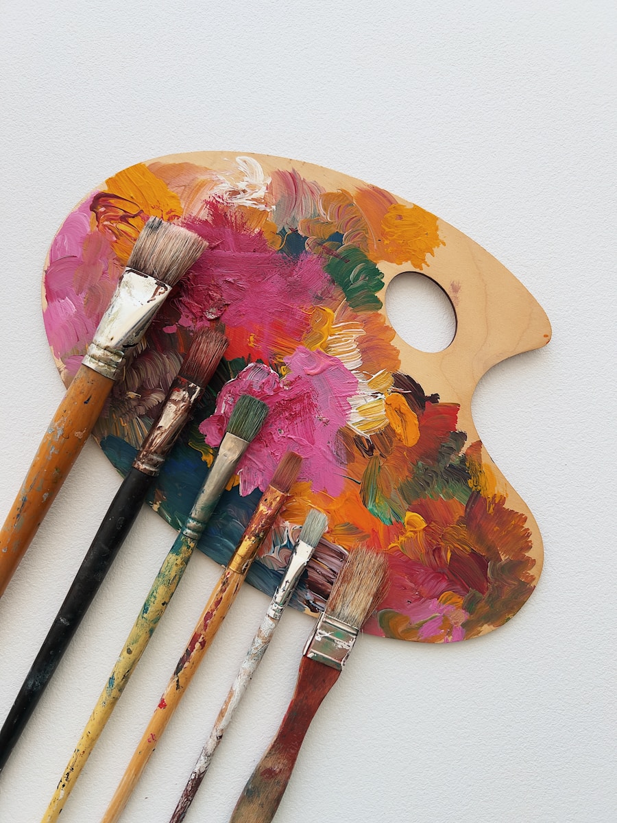 Six paintbrushes resting on a wooden palette covered in colorful oil paint